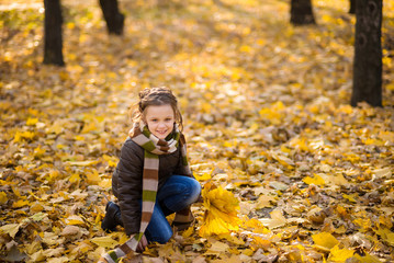 a teenager girl in jacket and jeans plays in the autumn park with golden leaves