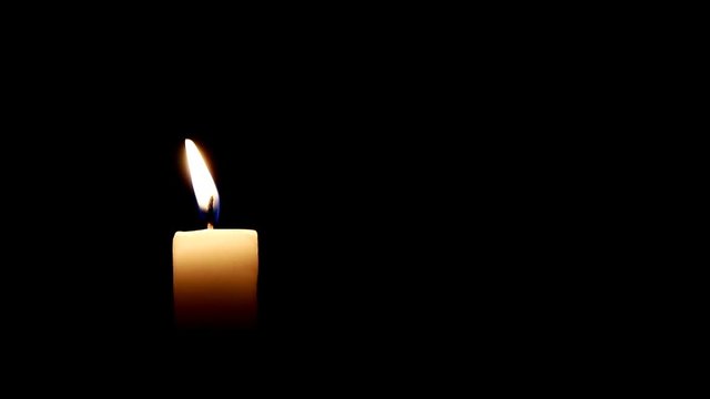 Burning candle on dark background.