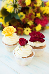 Three cupcakes with red and yellow roses. Selective focus