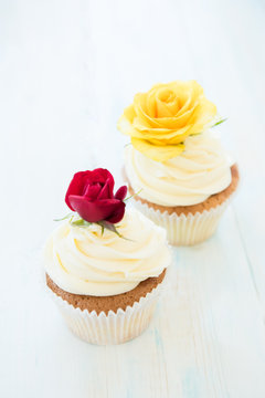 Two cupcakes with red and yellow roses. Selective focus