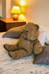 Happy teddy bear relaxing on comfortable bed