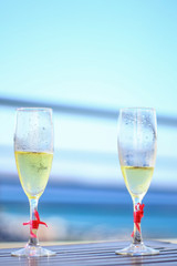 Two champagne glasses on a wooden table with ribbons 