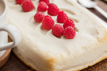 Cheesecake with raspberry and cup of coffe on wooden background.