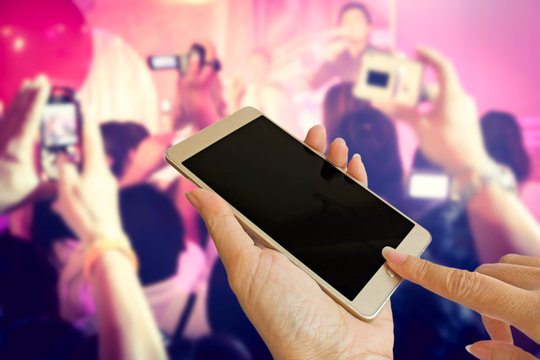 audiences hold smart phone to take photo  music band