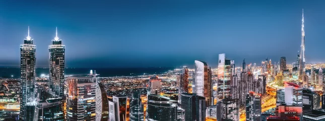 Foto auf Glas Scenic aerial view of downtown Dubai, United Arab Emirates, with illuminated skyscrapers. Artistic panoramic skyline. © Funny Studio