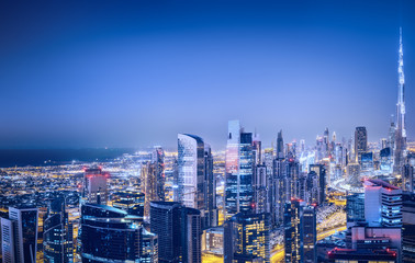 Fototapeta na wymiar Aerial panoramic view of a big futuristic city by night. Business bay, Dubai, United Arab Emirates. Nighttime skyline.