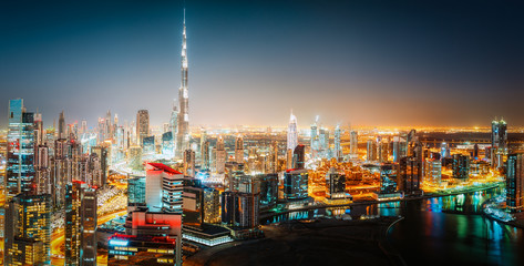 Aerial panorama view of a big futuristic city by night. Business bay, Dubai, United Arab Emirates. Colorful nighttime skyline.