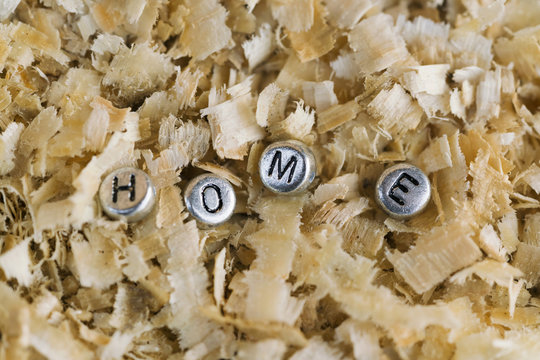 Inscription HOME made of silver metallic beads with letters on the background of sawdust
