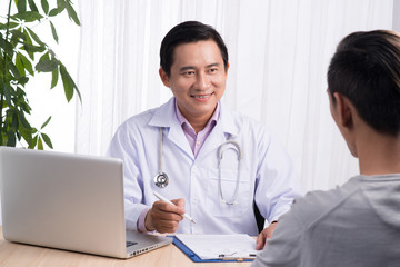 Confident asian male doctor discussing diagnosis with patient in