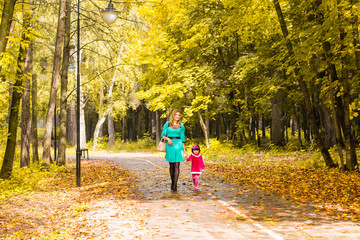 Fototapeta premium Mother and daughter walking holding hands at park. Family lifestyle, autumn season concept