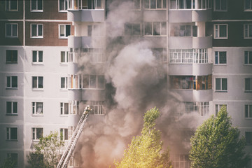 Firefighters extinguish a fire in multistory apartment building. Toned