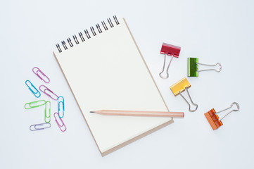 spiral notebook with pencil and colorful paper clips