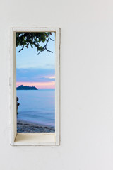 White wood wall window with sunset sea beach view.