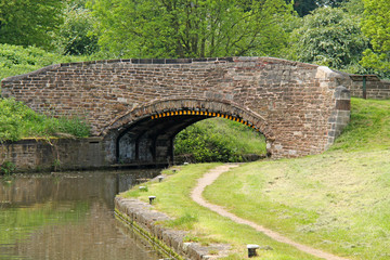Fototapeta na wymiar A Classic Stone Built Bridge Over a Canal and Towpath.