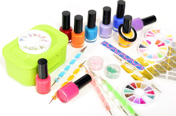 Table full of manicure ustensils, coloured nail polish,nail decals stickers, striping tape, nail file, dotting nail pens, vinyl sheets.  Nails art accesories isolated on white. 