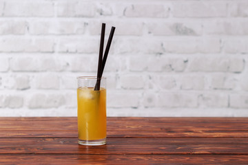 Orange juice with ice in glass and straw in cafe