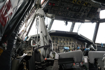 Cockpit of big airplane - seat and instrument panel with controls, joystick, displays, knobs and pilot lights