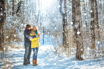 Fototapeta na wymiar A loving couple walking in winter park. The snowfall