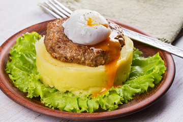 Beef and pork sausage patty with poached egg, smashed potatoes and lettuce
