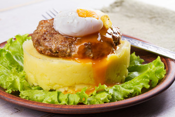 Beef and pork sausage patty with poached egg, smashed potatoes and lettuce