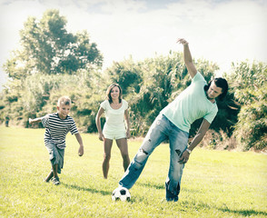 Naklejka premium Happy family with teenager playing in soccer