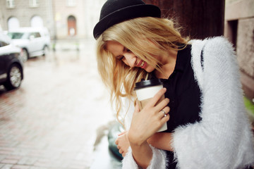 Cheerful woman in the street drinking morning coffee. Walking girl