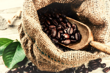 Roasted coffee beans in burlap sack with old wooden scoop