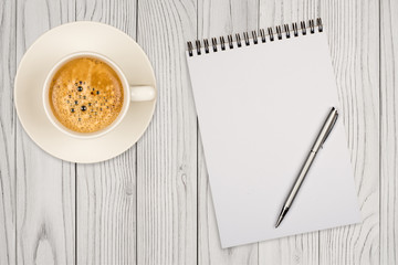 Coffee cup, spiral notebook and pen on the wooden table
