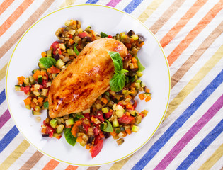 Fried chicken breast with sauteed vegetables: eggplant, carrot, zucchini, squash and tomatoes. View from above, top studio shot