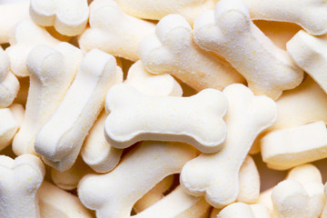 Pile of white color dog biscuits in the shape of a bone for a pet food background