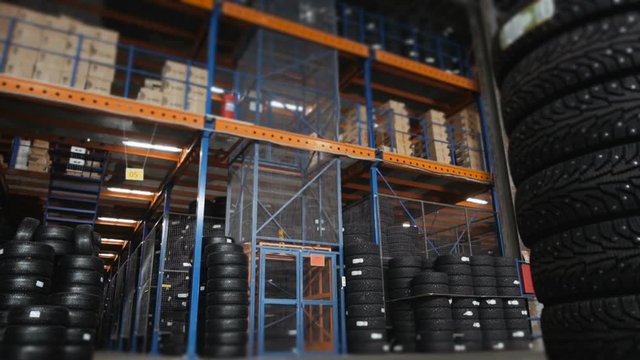 Car Tires At Warehouse In Tire Store. A Huge Warehouse of a Car Tires With Elevator