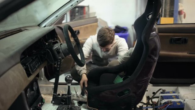 Mechanic installs a sports seat in the car