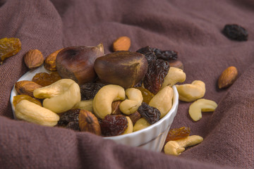 raisins and nuts in a saucer on the background of canvas