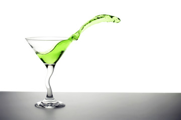 green cocktail splashing out of a martini glass