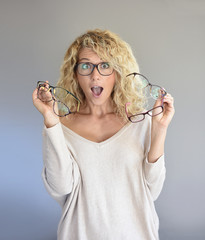 Blond woman with curly hair choosing between different eyeglasses