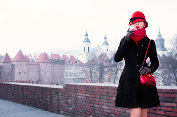 Obraz premium Winter fall fashion style woman in European city. Warsaw Poland. Red hat, handbag purse,scarf,and black wool coat. copy space. 