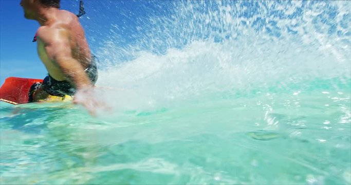 Young man kitesurfing in tropical blue ocean, extreme sport slow motion
