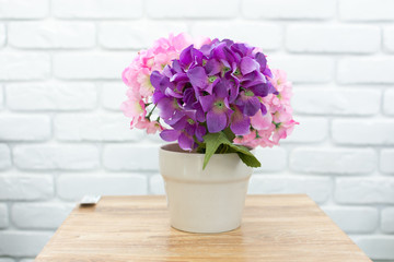   Vase of fake flowers on the table with white brick background