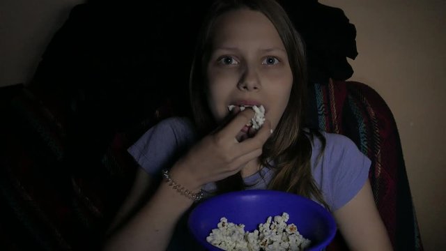 Girl watching movie in the cinema and eating pop corn greedily. 4K UHD