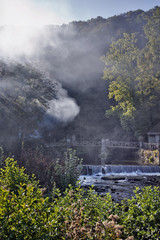 Fototapeta na wymiar Sunflare and mist on bridge and waterfall