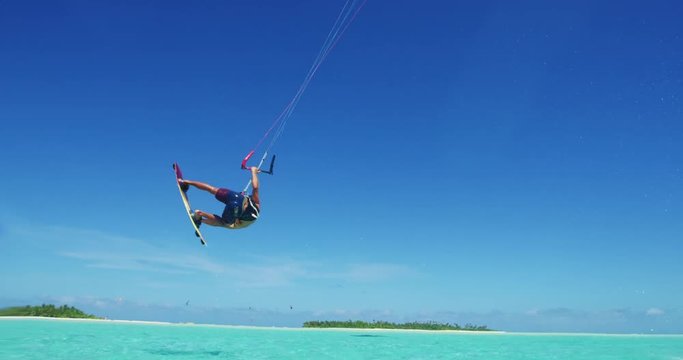 Young man kitesurfing in tropical blue ocean, extreme sport slow motion