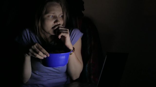 Girl watching horror movie on a laptop. 4K UHD