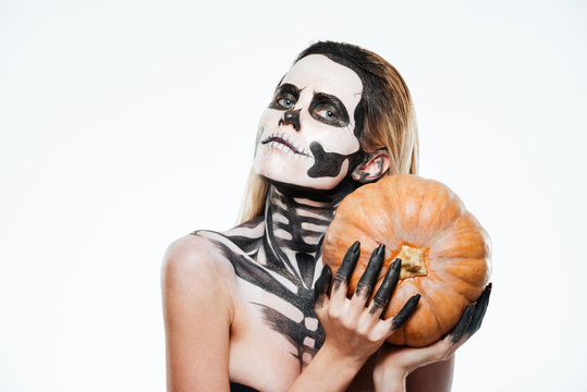 Portrait of woman with halloween skeleton makeup holding pumpkin