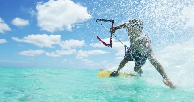Young man kitesurfing in tropical blue ocean, extreme sport slow motion