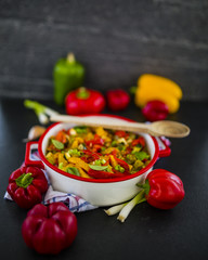 Delicious stewed colored peppers with onions, herbs and spices on dark stone background. vegetarian food. Healthy diet.