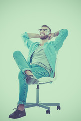 Fototapeta premium Young man sitting on the chair isolated over white background