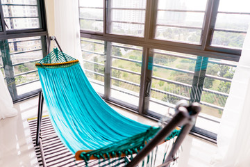 Blue hammock near window in modern interior.