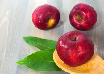 fresh red apple on wood background with green leaf