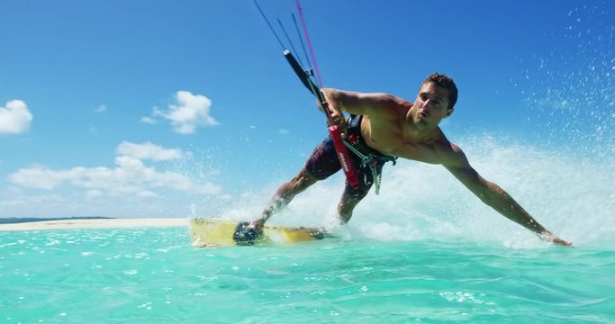 Young man kitesurfing in tropical blue ocean, extreme sport slow motion