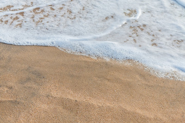 Fototapeta na wymiar Waves crashing on the beach sand
